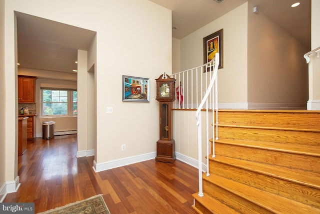 stairs with a baseboard heating unit and hardwood / wood-style flooring