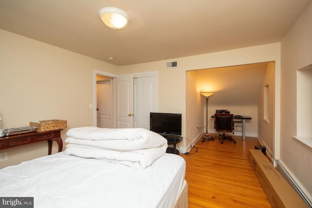 bedroom featuring light hardwood / wood-style flooring, a closet, and baseboard heating