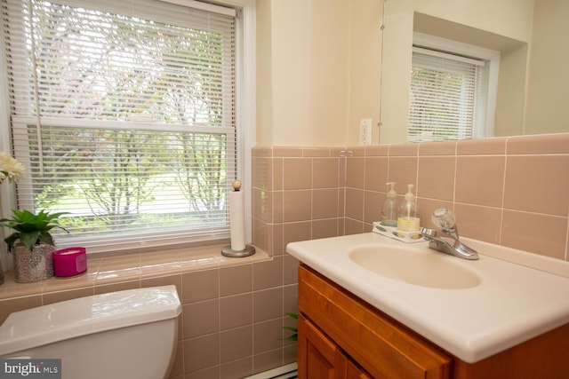 bathroom featuring tile walls, vanity, a wealth of natural light, and toilet