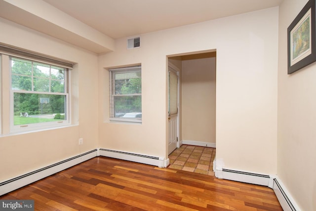 tiled spare room featuring a baseboard heating unit