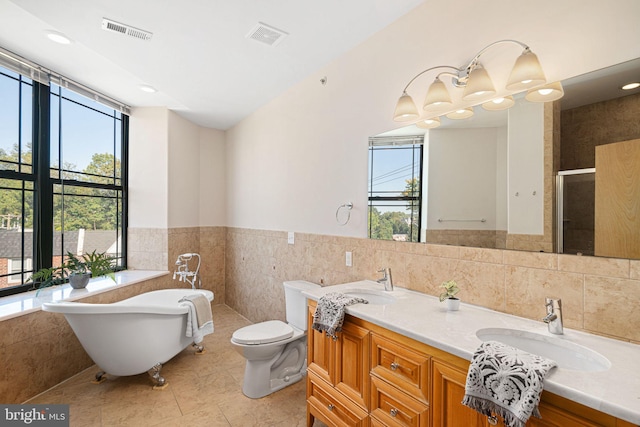 full bathroom featuring tile patterned flooring, toilet, separate shower and tub, tile walls, and vanity