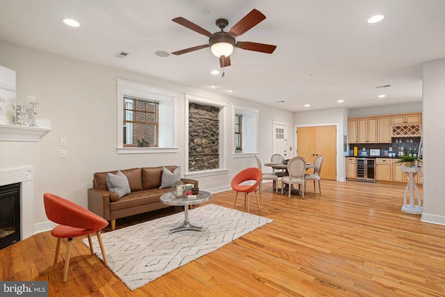 living room with beverage cooler, light hardwood / wood-style flooring, and ceiling fan