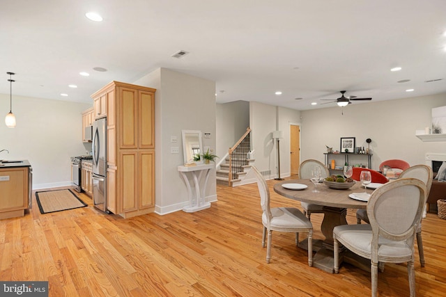 dining room with sink, light wood-type flooring, and ceiling fan