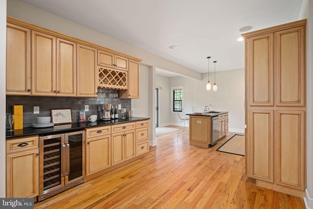 kitchen with hanging light fixtures, stainless steel dishwasher, beverage cooler, backsplash, and light hardwood / wood-style floors