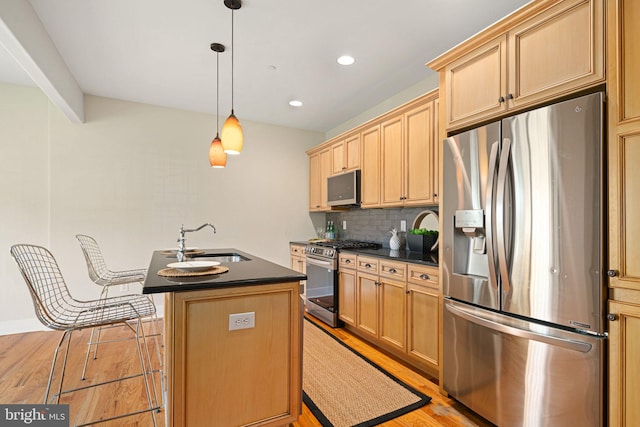 kitchen featuring light hardwood / wood-style floors, backsplash, sink, stainless steel appliances, and an island with sink