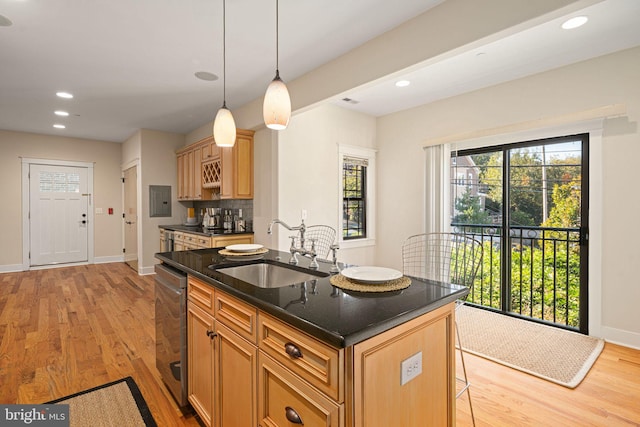 kitchen featuring hanging light fixtures, a center island with sink, sink, and light wood-type flooring