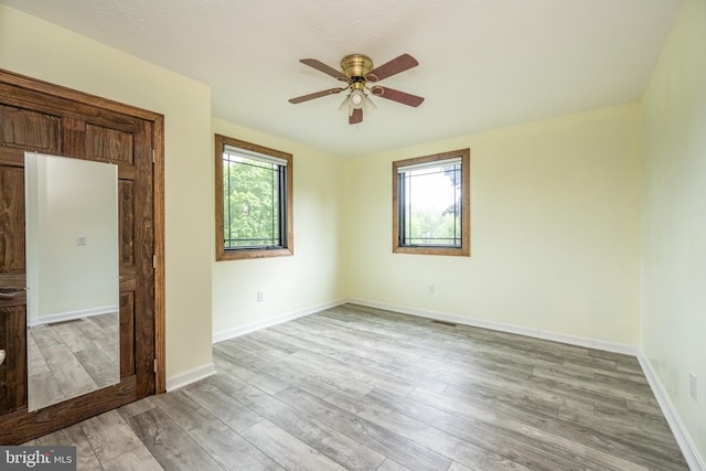 interior space featuring light wood-type flooring, ceiling fan, and multiple windows