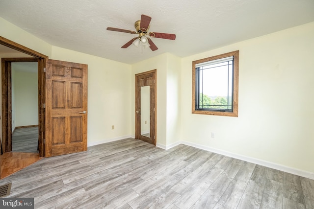 unfurnished bedroom featuring light hardwood / wood-style floors, ceiling fan, and a textured ceiling