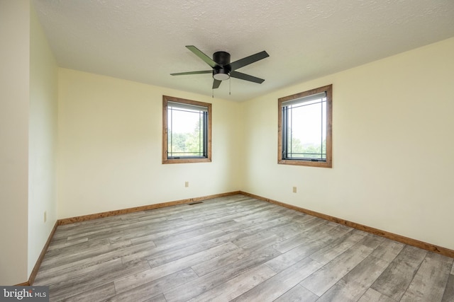 unfurnished room featuring ceiling fan, light hardwood / wood-style flooring, and a textured ceiling