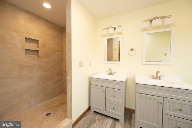 bathroom with tiled shower, hardwood / wood-style floors, and vanity