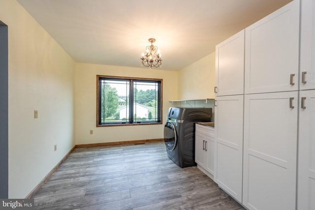 laundry area with light hardwood / wood-style floors, washer / dryer, an inviting chandelier, and cabinets