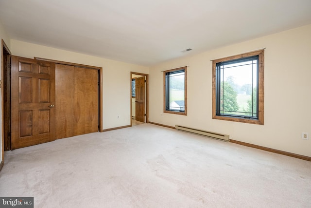 unfurnished bedroom featuring a baseboard radiator, light colored carpet, and a closet