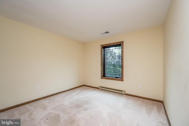 spare room featuring a baseboard heating unit and light colored carpet