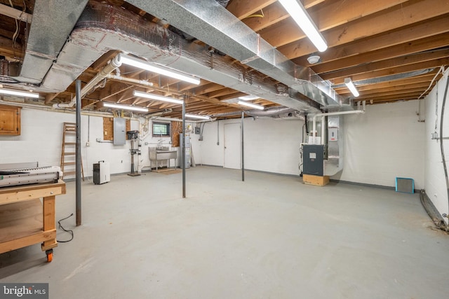 basement featuring water heater, heating unit, sink, and electric panel