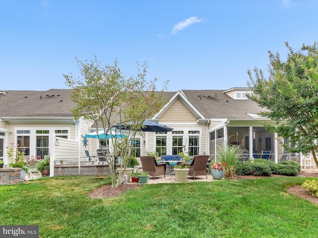 rear view of property with a sunroom, a patio, and a lawn