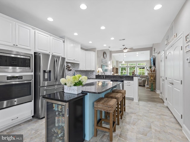 kitchen with a kitchen breakfast bar, kitchen peninsula, white cabinetry, and appliances with stainless steel finishes