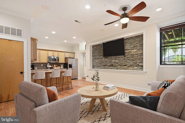 living room featuring ceiling fan, sink, light hardwood / wood-style flooring, and ornamental molding