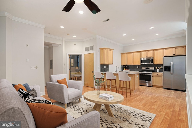 living room featuring sink, crown molding, light hardwood / wood-style flooring, and ceiling fan