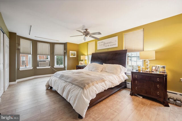 bedroom with ceiling fan, wood-type flooring, and multiple windows