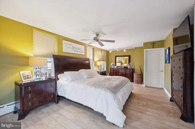 bedroom with baseboard heating, track lighting, ceiling fan, and light hardwood / wood-style floors