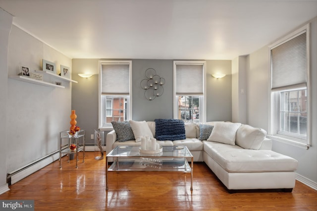 living room featuring wood-type flooring, plenty of natural light, and a baseboard radiator