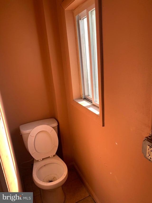 bathroom with toilet, tile patterned flooring, and a healthy amount of sunlight