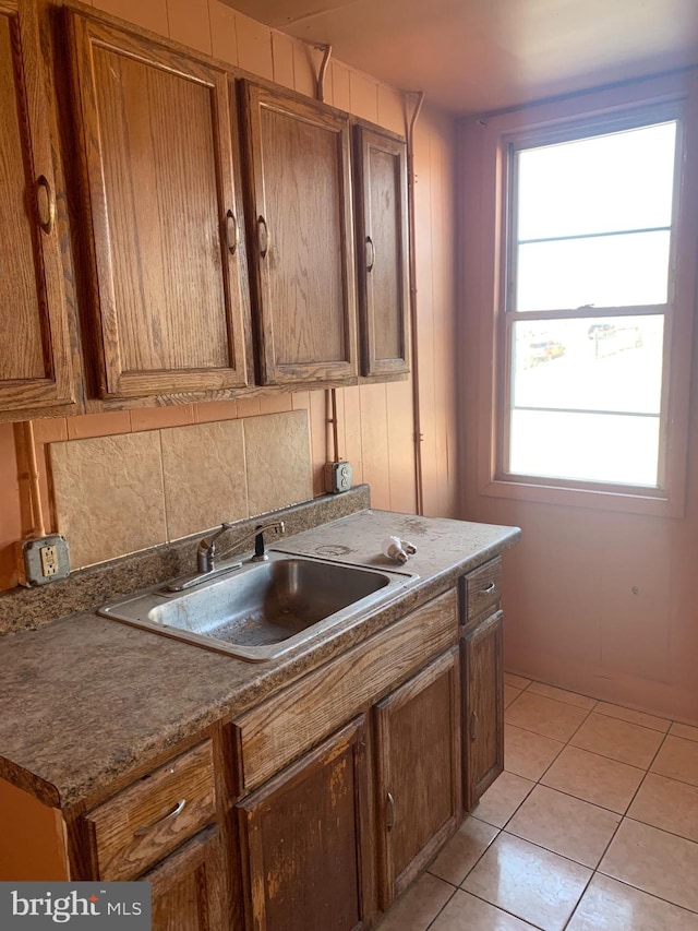 kitchen with light tile patterned flooring, sink, and backsplash