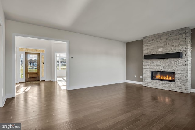 unfurnished living room featuring dark hardwood / wood-style flooring and a stone fireplace