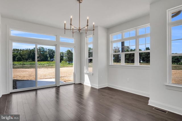 unfurnished dining area featuring plenty of natural light, dark hardwood / wood-style flooring, and a chandelier