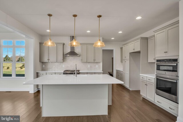 kitchen with an inviting chandelier, hanging light fixtures, tasteful backsplash, an island with sink, and dark hardwood / wood-style flooring