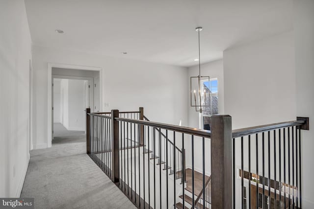 corridor featuring light colored carpet and an inviting chandelier