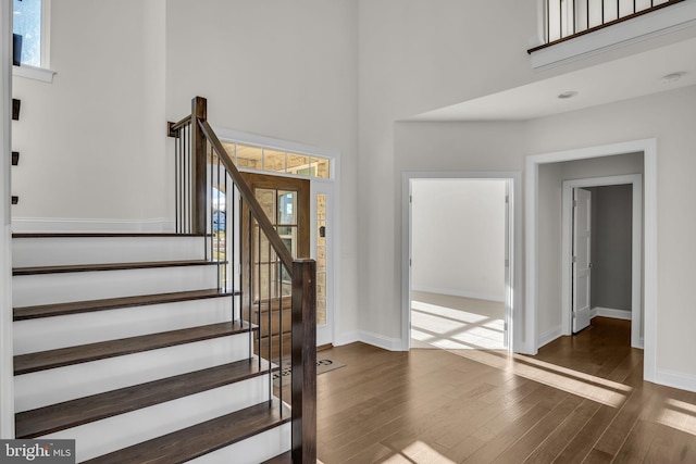 stairs with hardwood / wood-style flooring and a towering ceiling