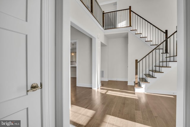 entrance foyer with hardwood / wood-style flooring and a towering ceiling