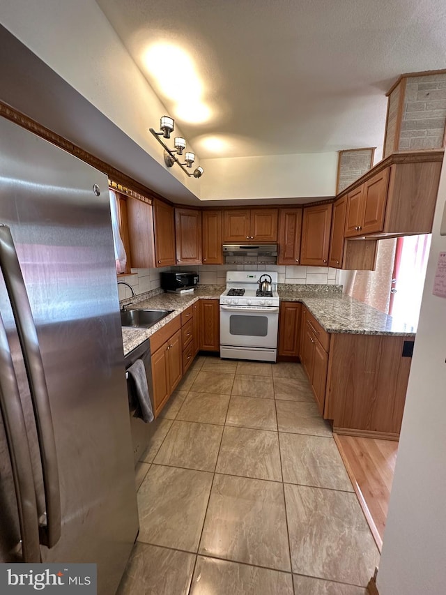 kitchen with black appliances, light stone counters, brown cabinetry, and a sink