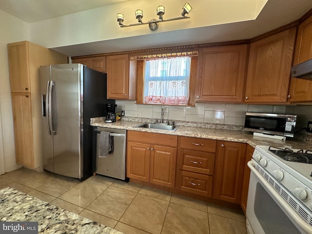 kitchen with stainless steel appliances, brown cabinetry, a sink, and decorative backsplash