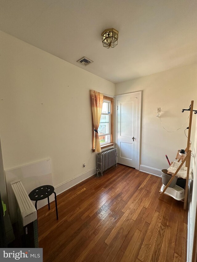 unfurnished room with radiator heating unit and hardwood / wood-style floors