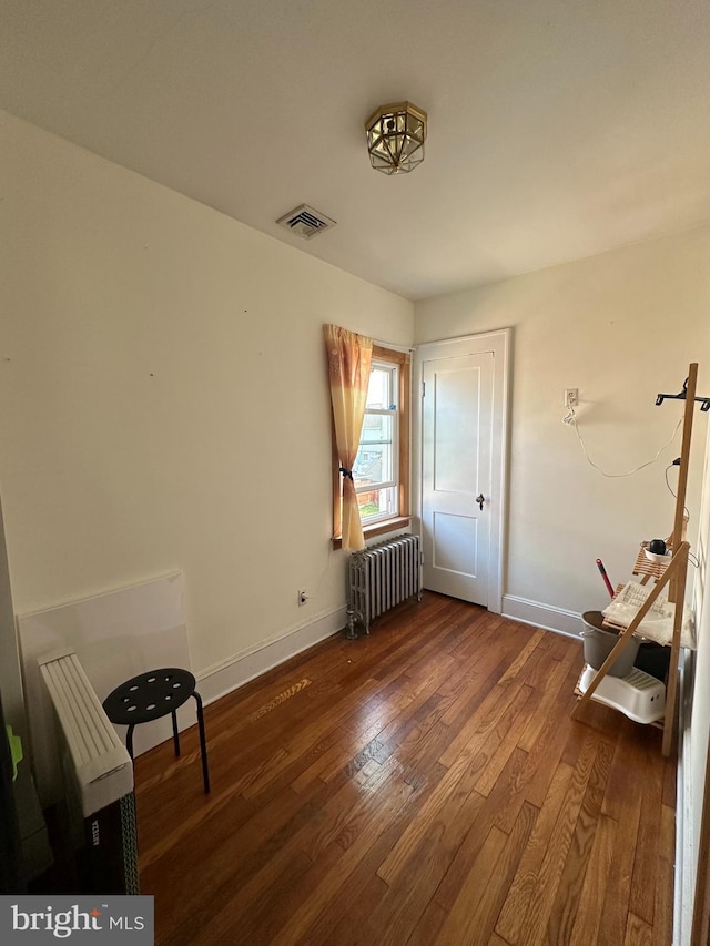 unfurnished bedroom featuring radiator, baseboards, visible vents, and dark wood-style flooring