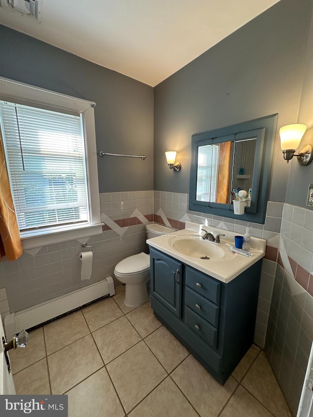 half bath featuring toilet, a baseboard radiator, tile patterned flooring, vanity, and tile walls