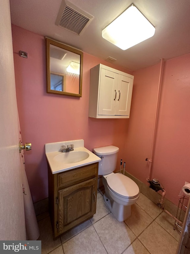 half bathroom featuring visible vents, vanity, toilet, and tile patterned floors