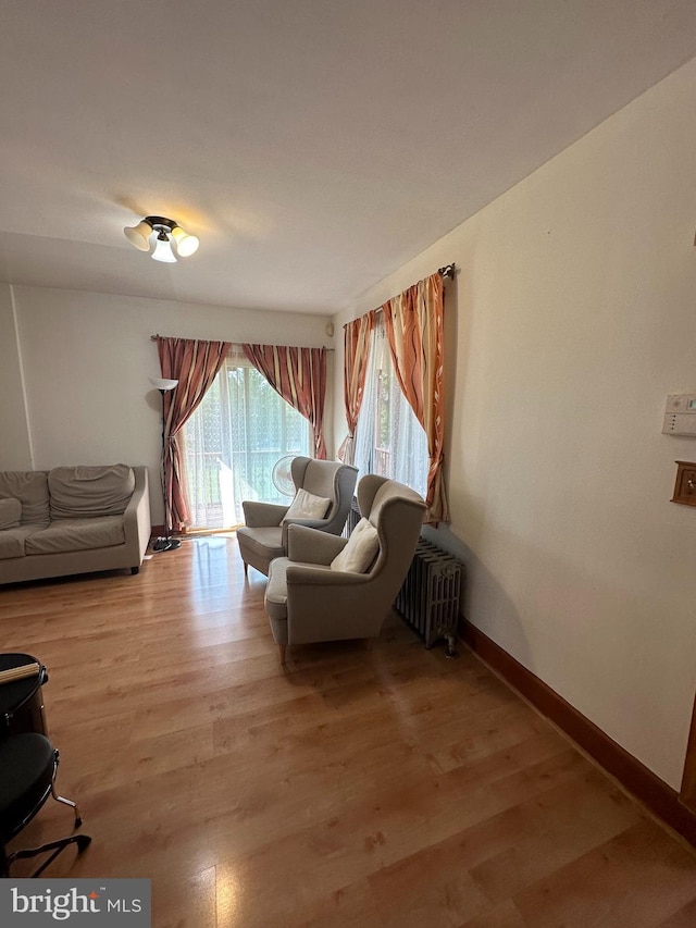 living area featuring baseboards, radiator heating unit, and light wood-style floors