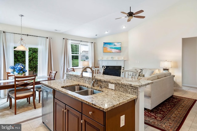 kitchen featuring pendant lighting, lofted ceiling, stainless steel dishwasher, light tile patterned floors, and sink