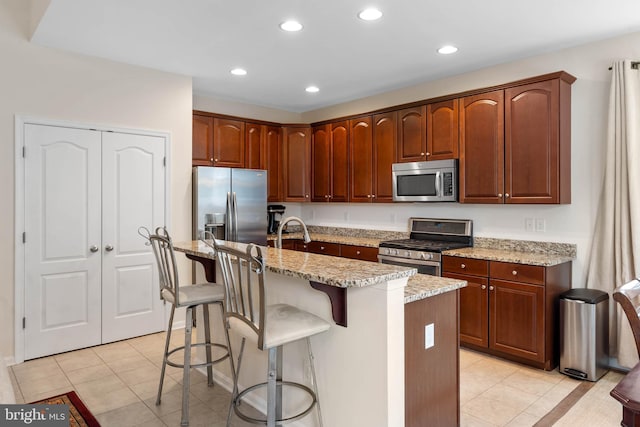 kitchen featuring a center island with sink, light tile patterned floors, and appliances with stainless steel finishes