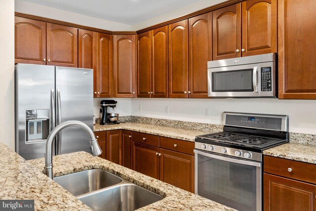 kitchen with hanging light fixtures, appliances with stainless steel finishes, a breakfast bar area, light tile patterned flooring, and light stone counters