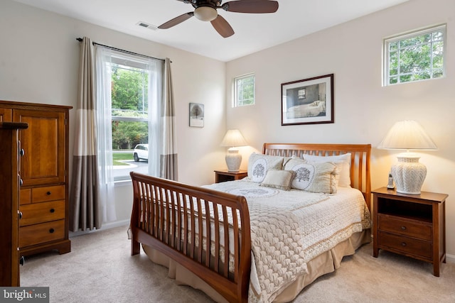 bedroom featuring ceiling fan, light colored carpet, and multiple windows