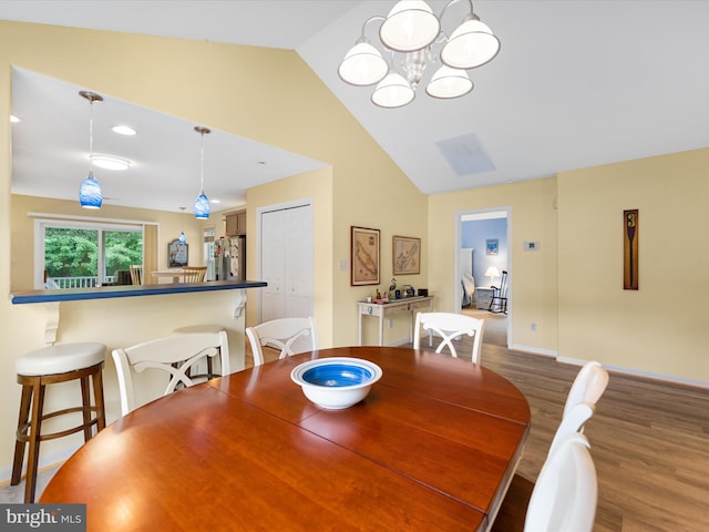 dining space with hardwood / wood-style floors, lofted ceiling, and a chandelier