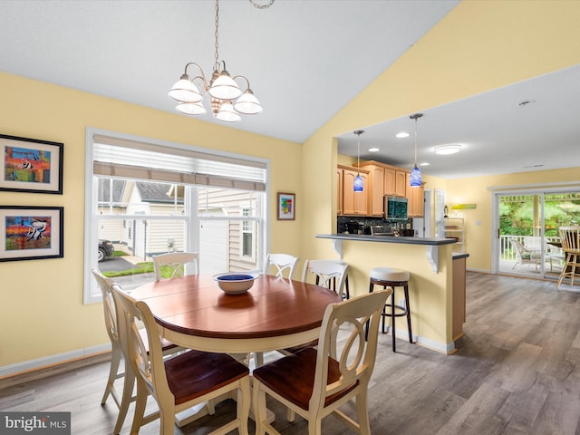 dining area with lofted ceiling, dark hardwood / wood-style floors, and a notable chandelier