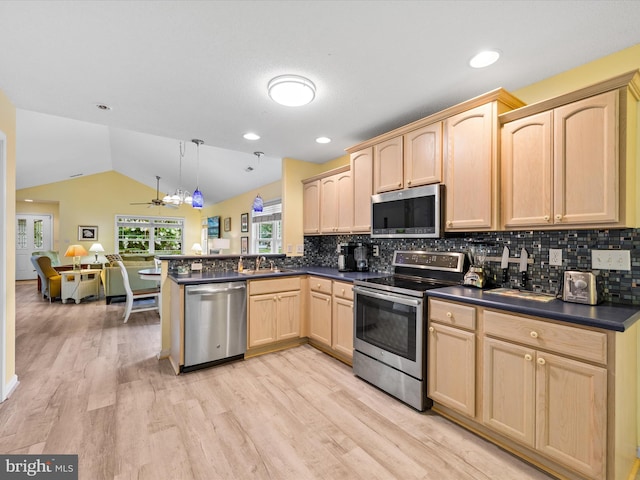 kitchen featuring light hardwood / wood-style flooring, lofted ceiling, appliances with stainless steel finishes, kitchen peninsula, and hanging light fixtures