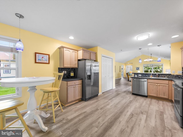 kitchen with pendant lighting, lofted ceiling, appliances with stainless steel finishes, and light wood-type flooring