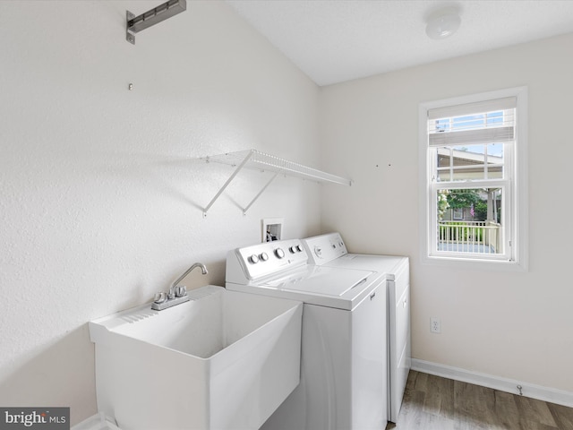 laundry room with washer and dryer, hardwood / wood-style flooring, and sink