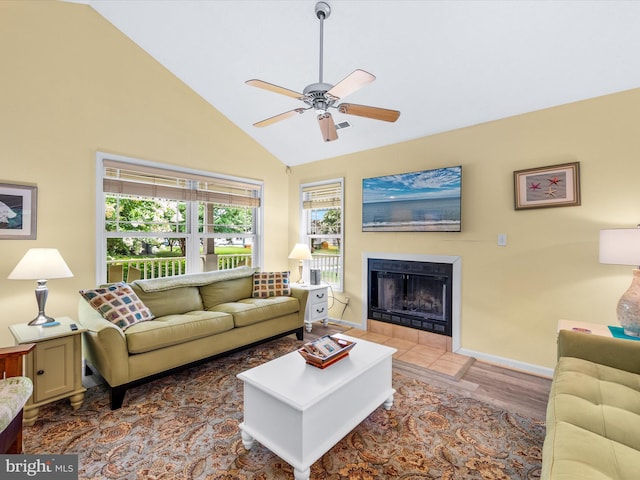 living room featuring a tiled fireplace, wood-type flooring, lofted ceiling, and ceiling fan